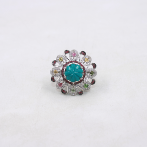 Ring with a turquoise center stone and multicolored gemstones on a white background