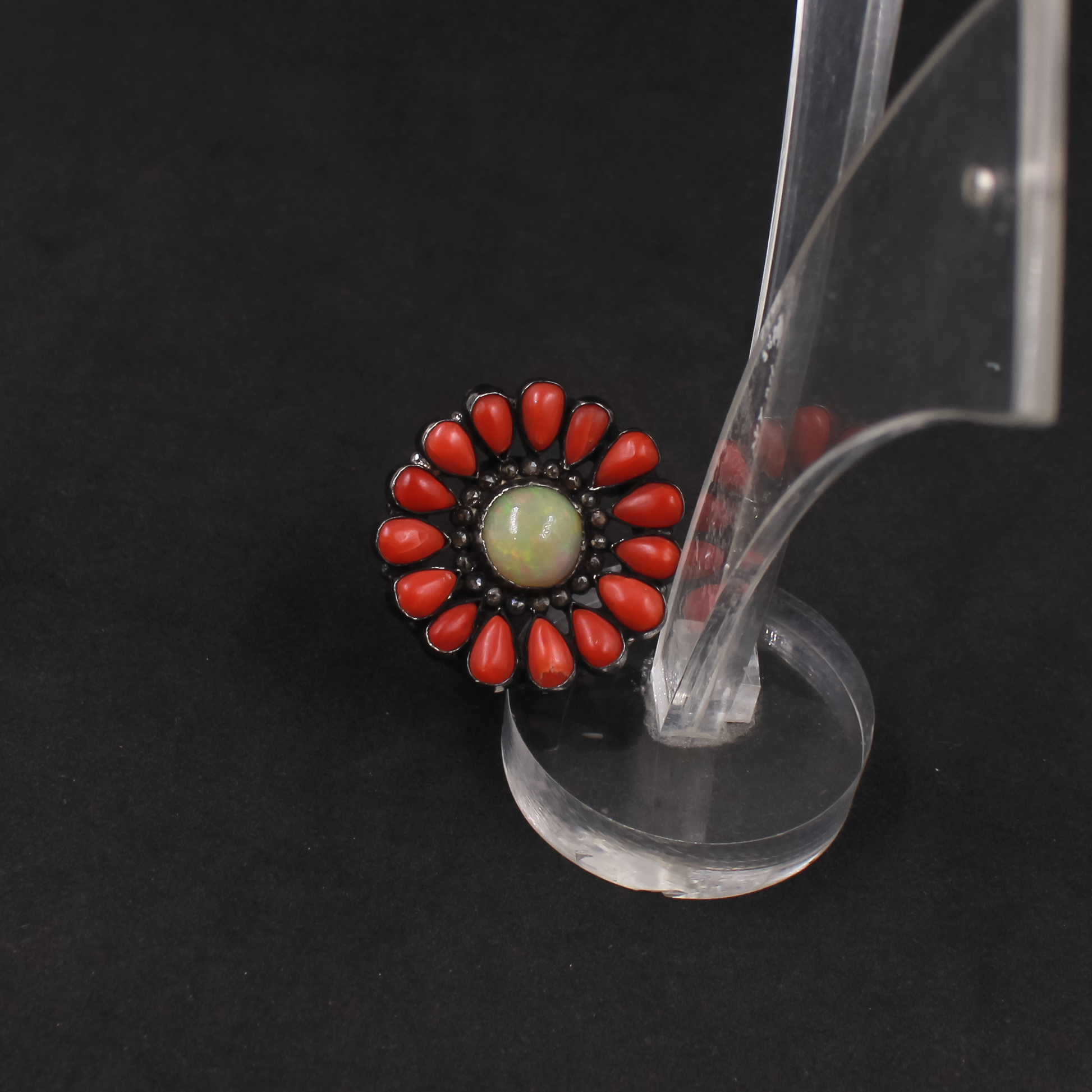 Close-up of a decorative ring with red stones and a central green stone on a black background.