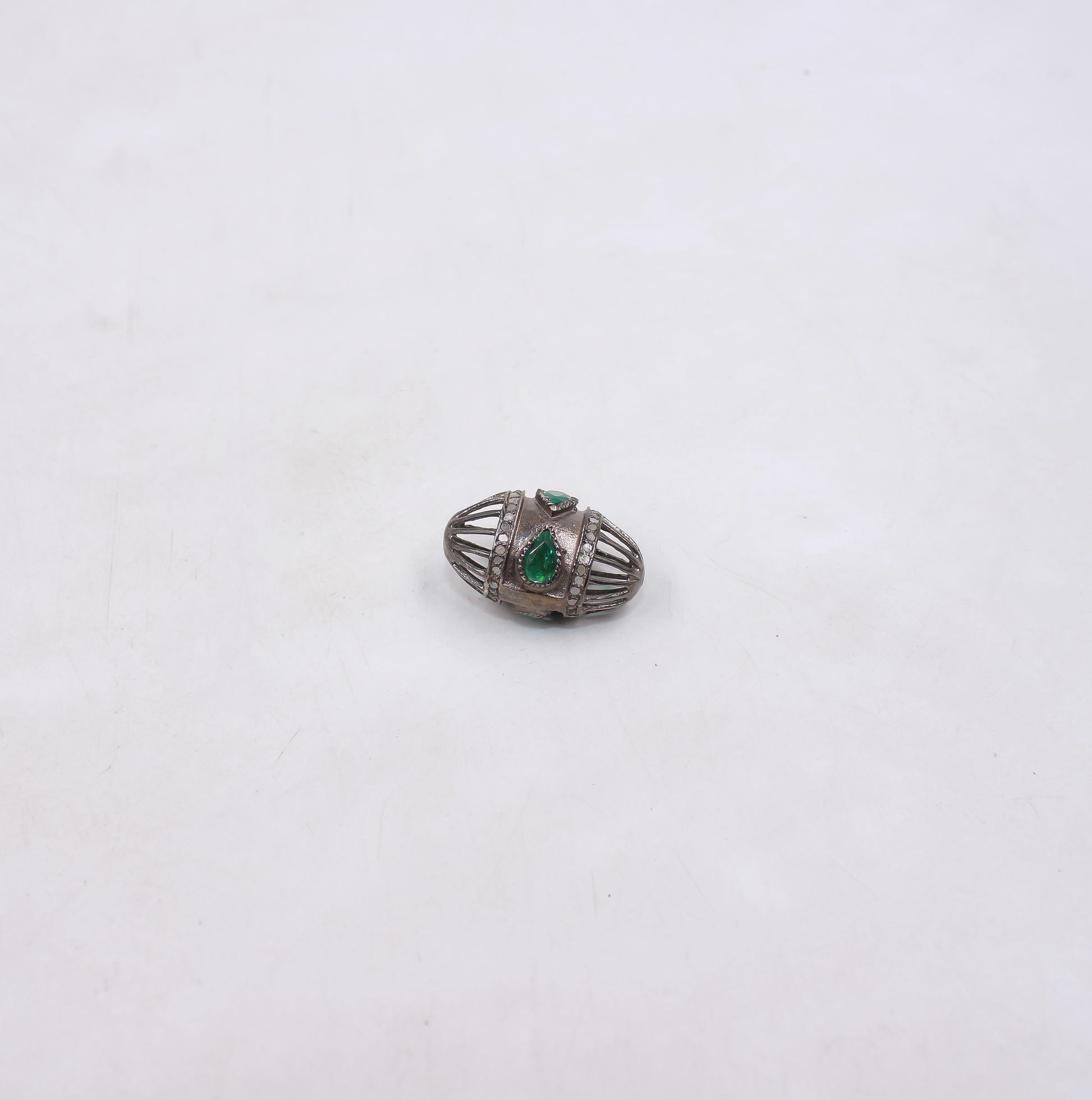 Silver brooch with green gemstones on a white background