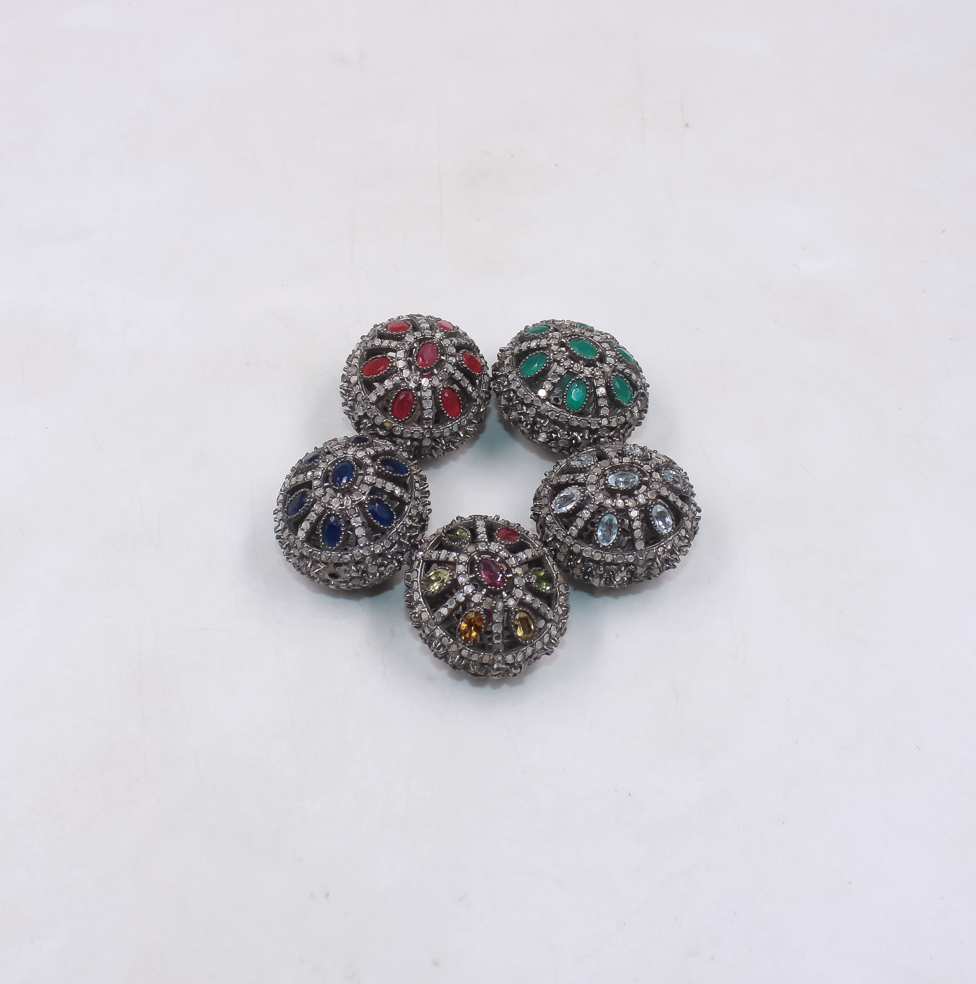 Five decorative beads with multicolored gemstones on a white background