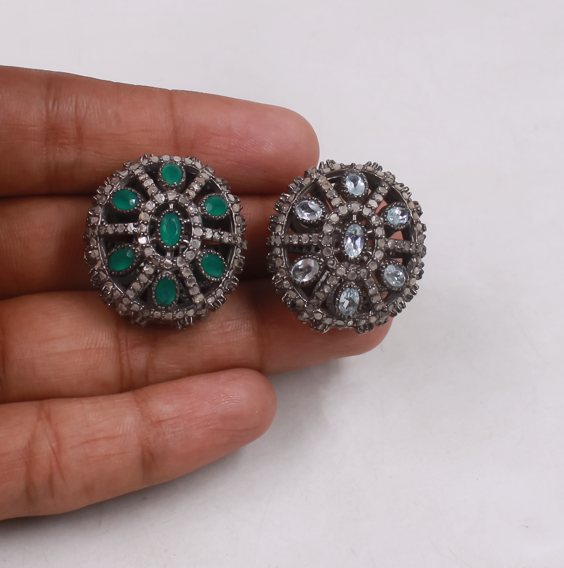 Beads with gemstone-like elements held between fingers on a light background