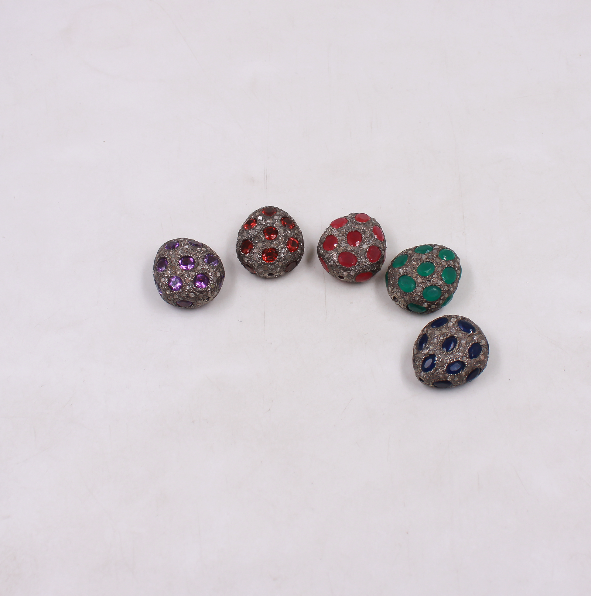 Five decorative buttons with colored gemstones on a white background