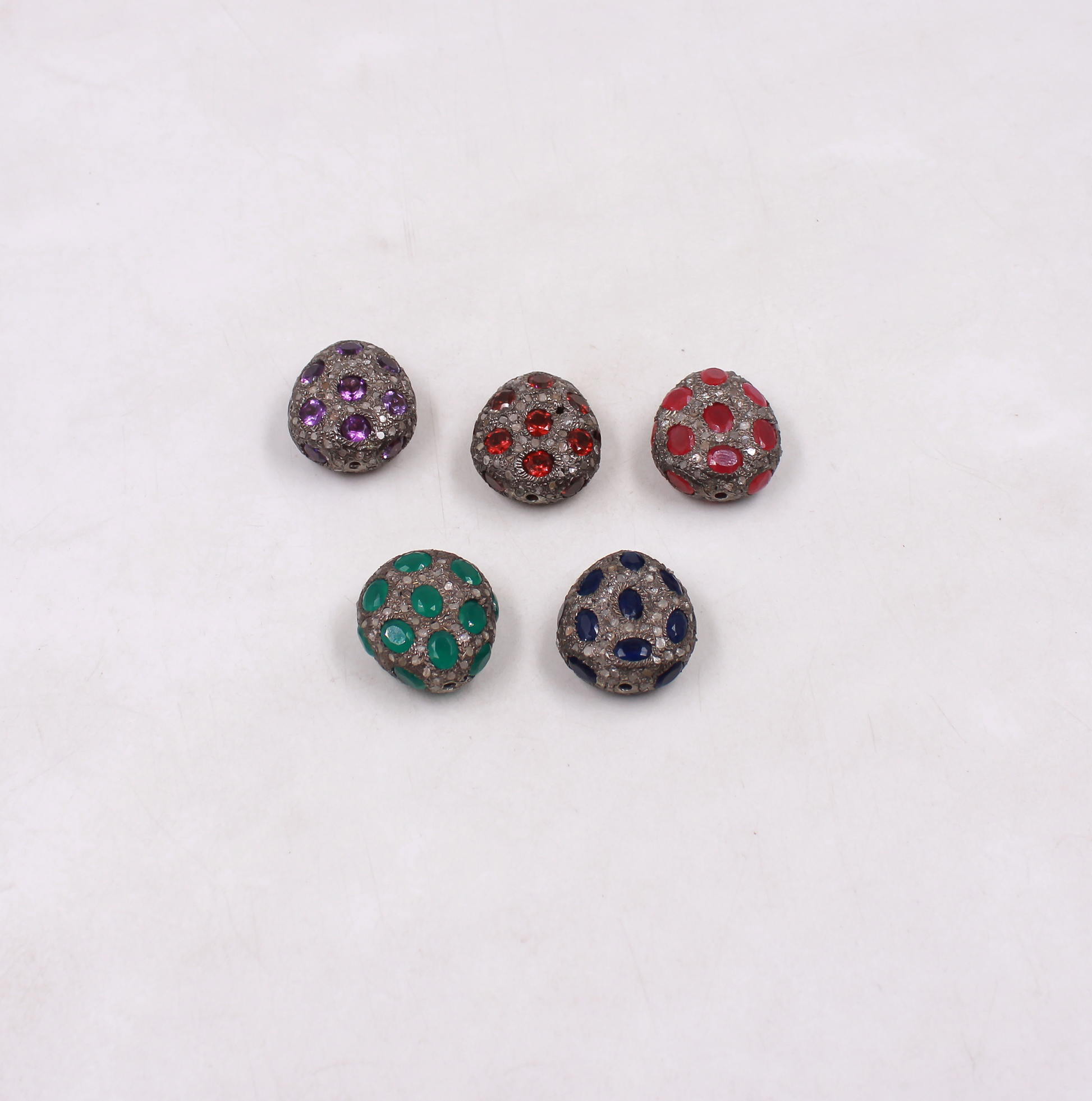 Five round jewelry pieces with colored gemstones on a white background
