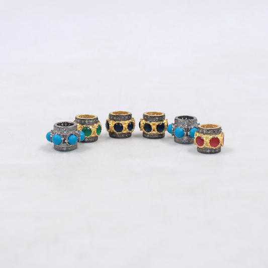 Set of six decorative cylindrical beads with colorful gemstones on a white background