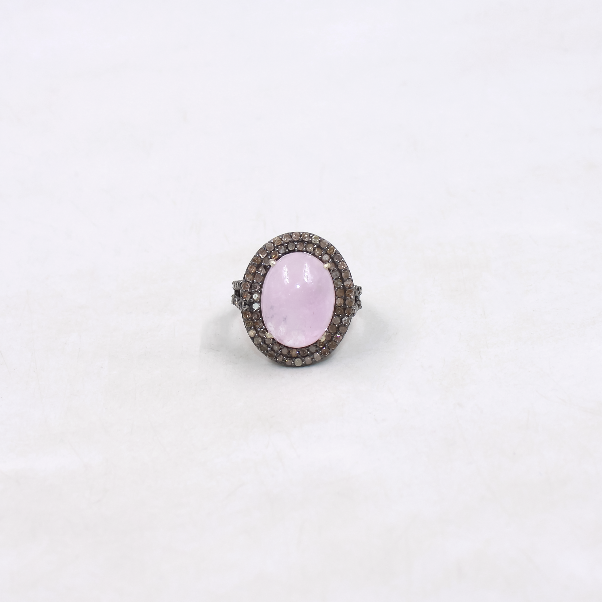 Ring with a pink gemstone and diamond-studded band on a white background