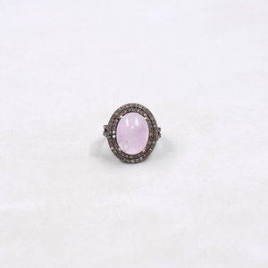 Ring with a pink gemstone and diamond-studded band on a white background