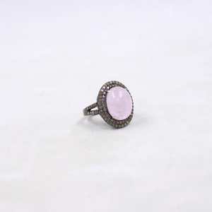 Ring with a pink stone and diamond-studded band on a white background