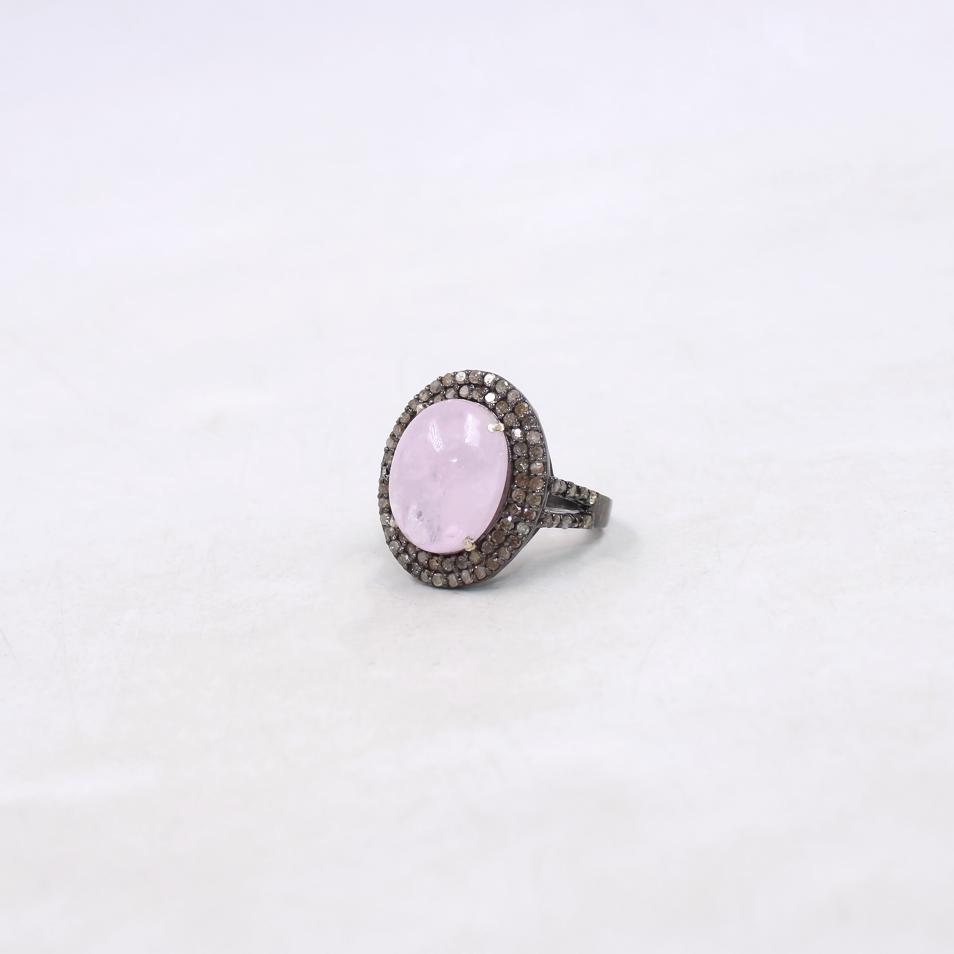 Ring with a pink stone and black diamond accents on a white background