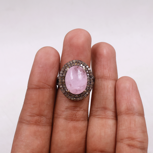 Ring with a pink gemstone on a hand against a white background