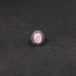Ring with a pink gemstone and diamond-studded band on a dark gray background