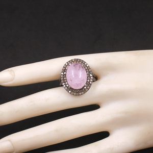 Ring with a pink stone on a mannequin hand against a black background