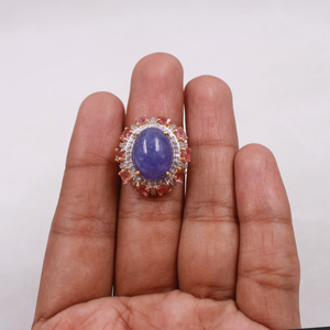 Ring with a purple gemstone held on a person's finger against a white background