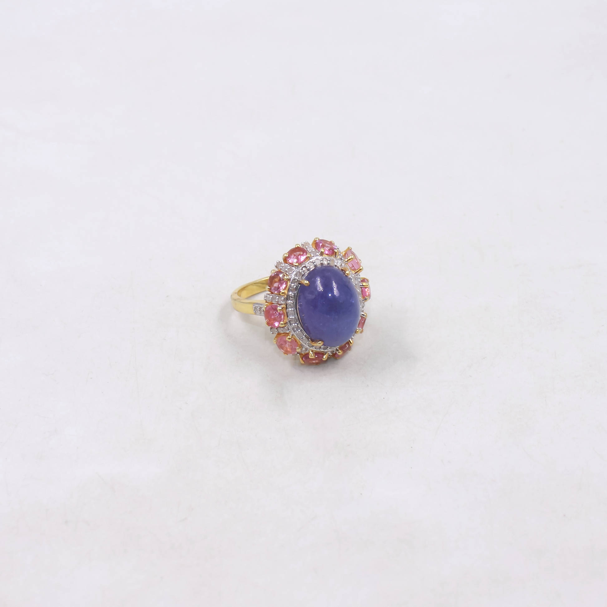 Ring with a purple gemstone and pink accents on a white background