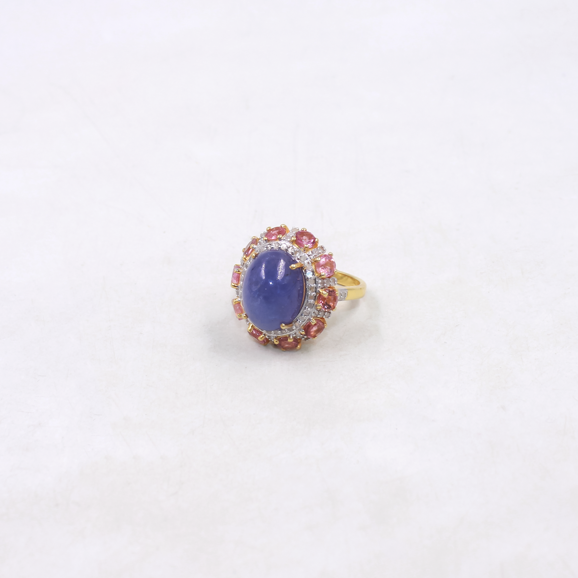 Ring with a purple gemstone and smaller pink stones on a white background