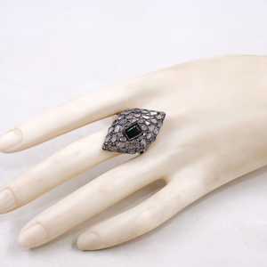 Ring with a green gemstone on a mannequin hand against a white background