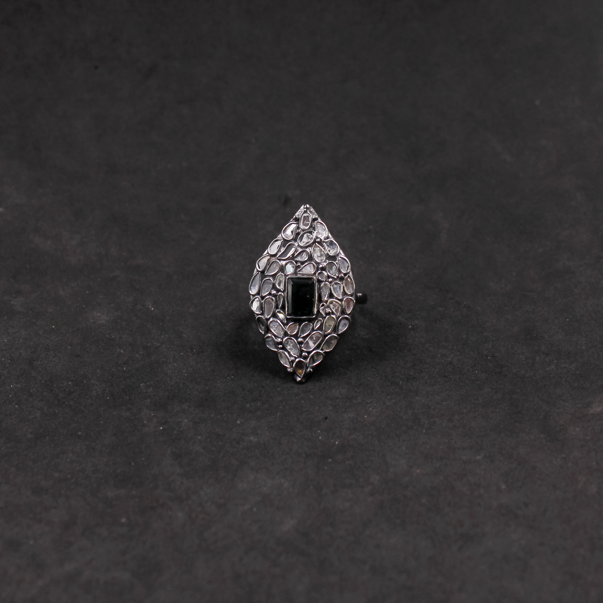 Silver ring with black gemstone on a dark gray background