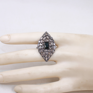 Silver ring with a central gemstone on a mannequin hand against a white background