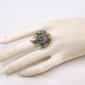Multicolored gemstone ring on a mannequin hand against a white background