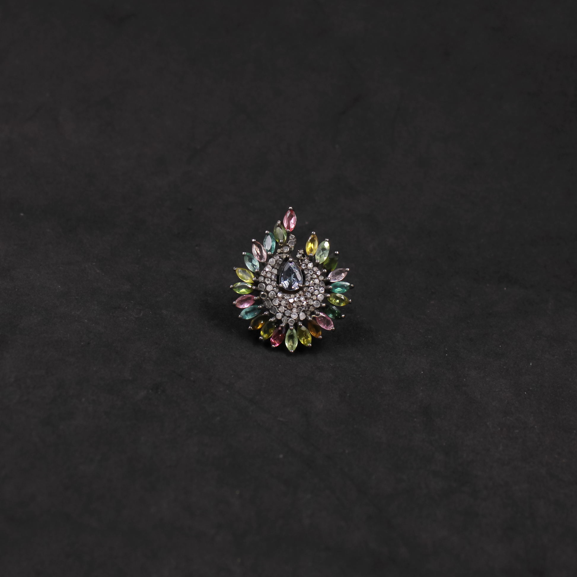 Decorative brooch with multicolored gemstones on a black background