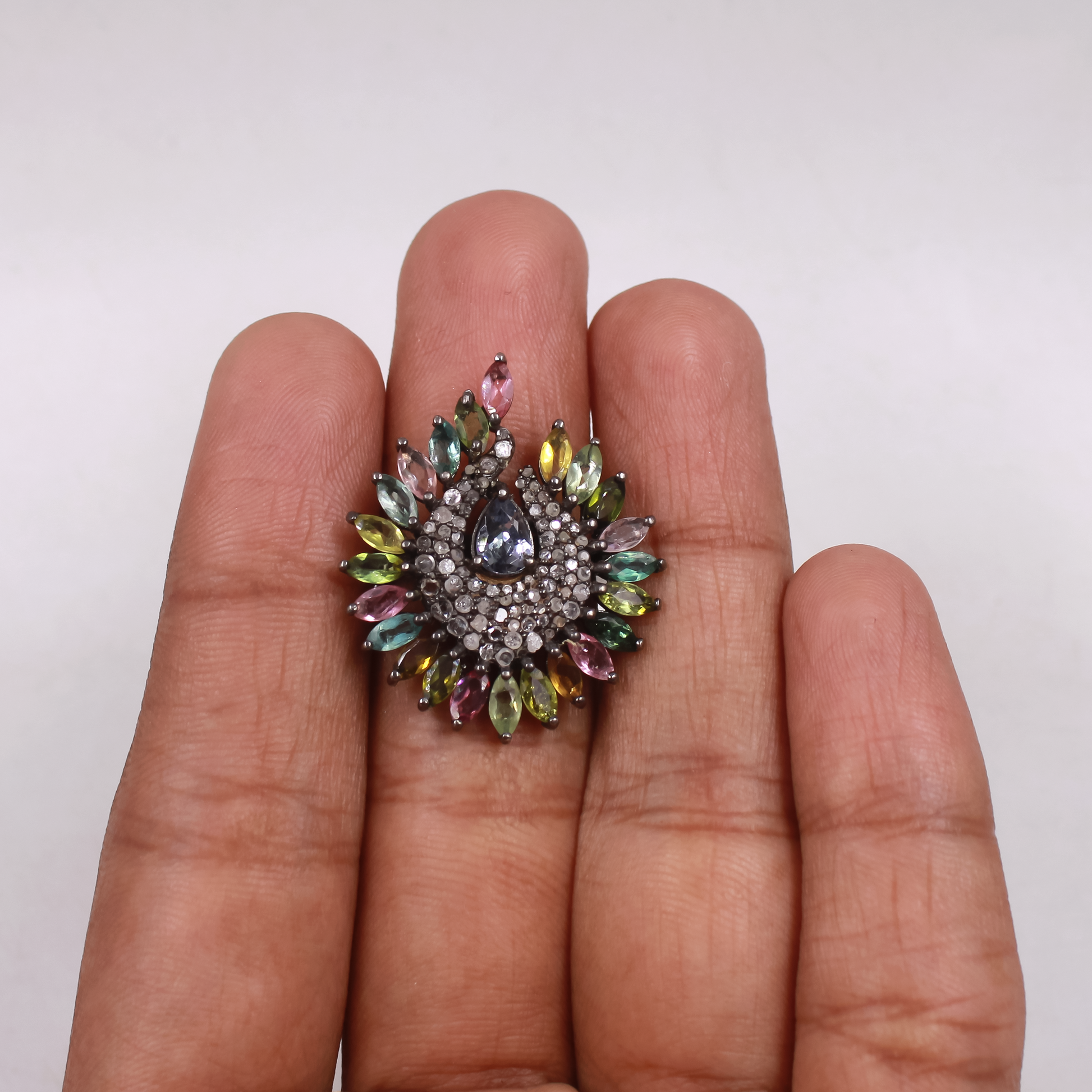 Multicolored gemstone ring on a person's finger against a white background