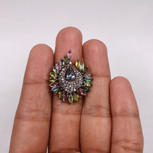 Multicolored gemstone ring on a person's finger against a white background
