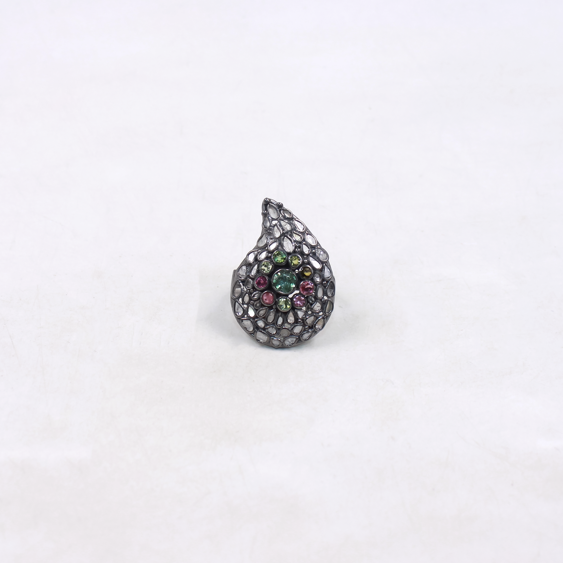 Teardrop-shaped ring with gemstones on a white background