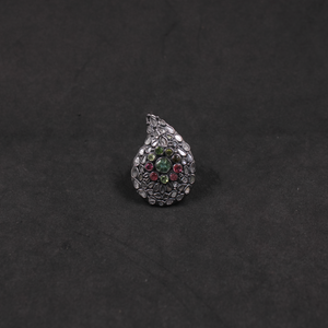 Teardrop-shaped silver ring with colored gemstones on a black background