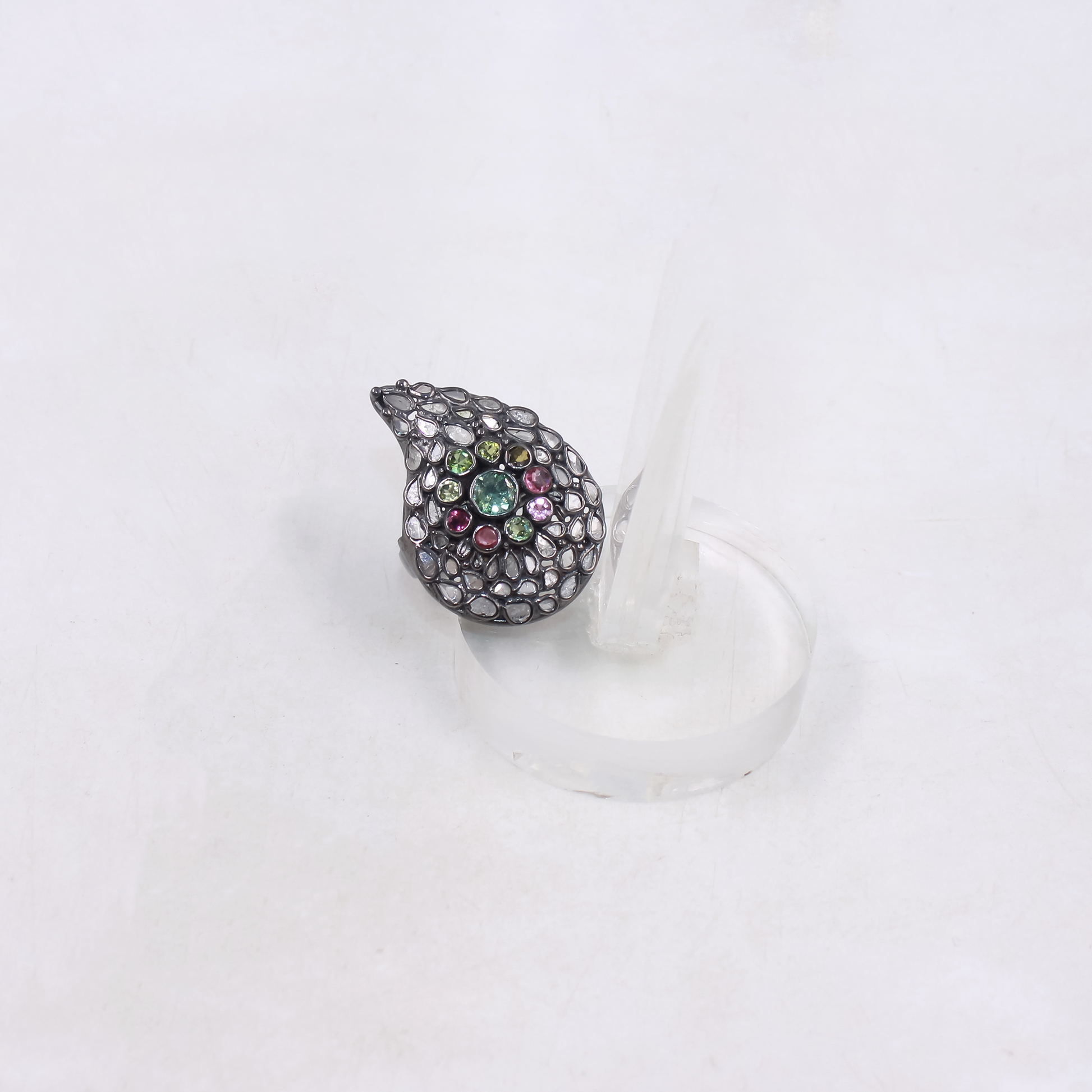 Teardrop-shaped jewelry piece with multicolored stones on a white background