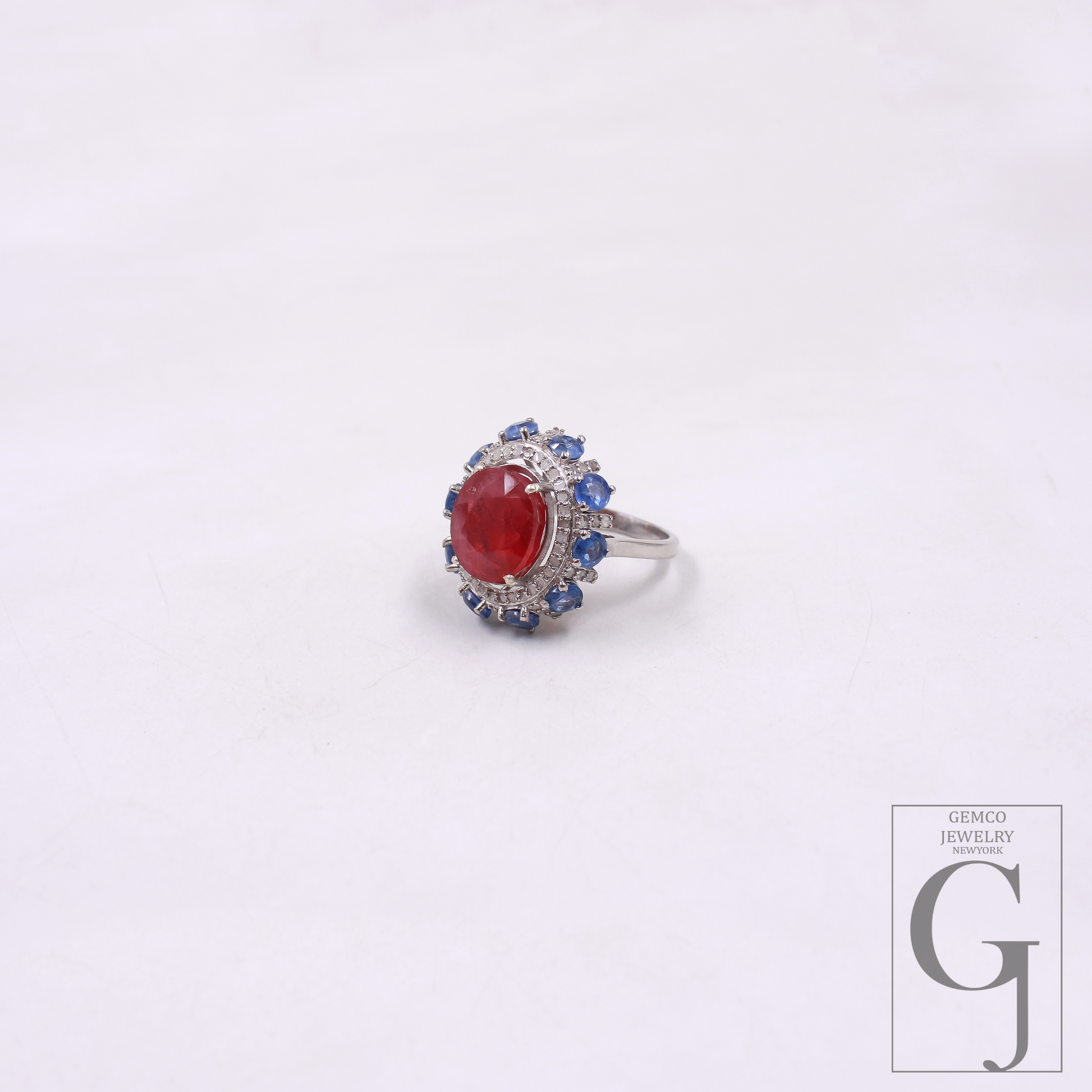Ring with a red gemstone and blue accents on a white background