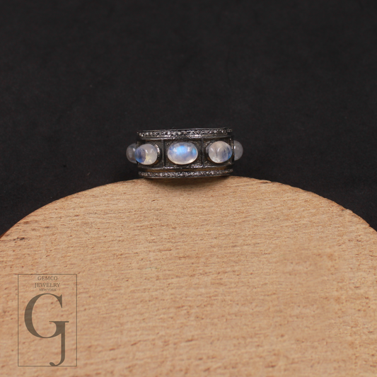 Ring with moonstones on a wooden stand against a black background