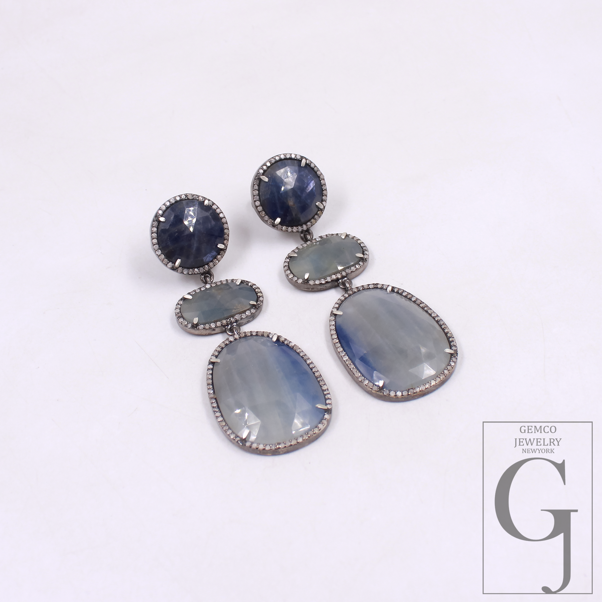 Pair of earrings with Blue Sapphire on a white background, featuring the Gemco Jewelry logo.