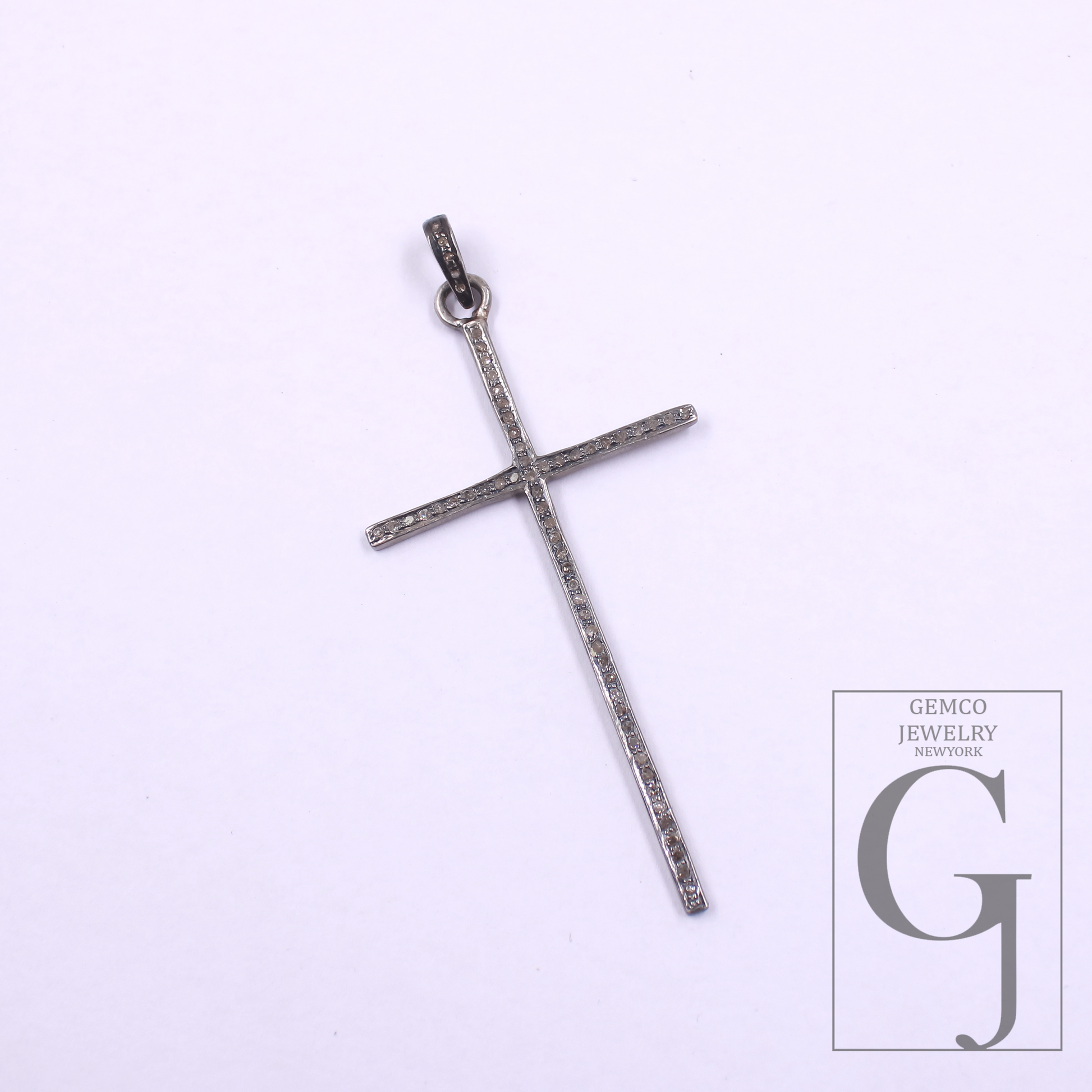 Silver cross pendant on a light purple background with 'GEMCO JEWELRY' logo.