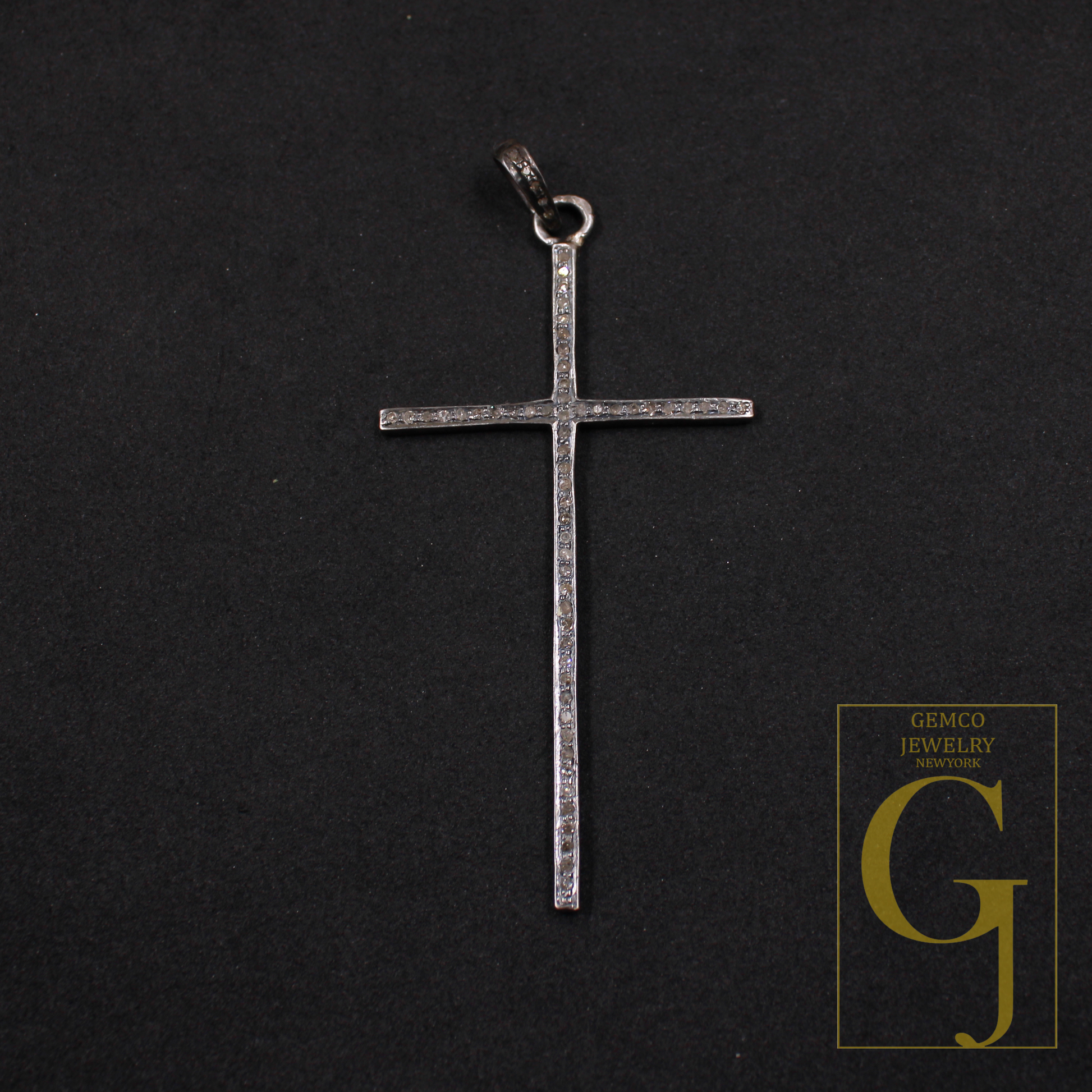Silver cross pendant on a black background with Gemco Jewelry New York logo.