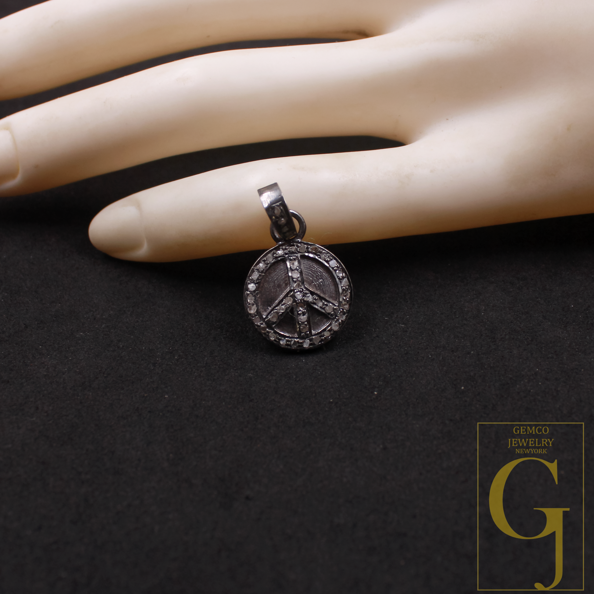 Silver peace symbol pendant on a mannequin hand against a black background