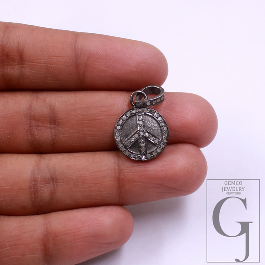 Silver peace symbol pendant held between fingers with Gemco Jewelry New York logo.