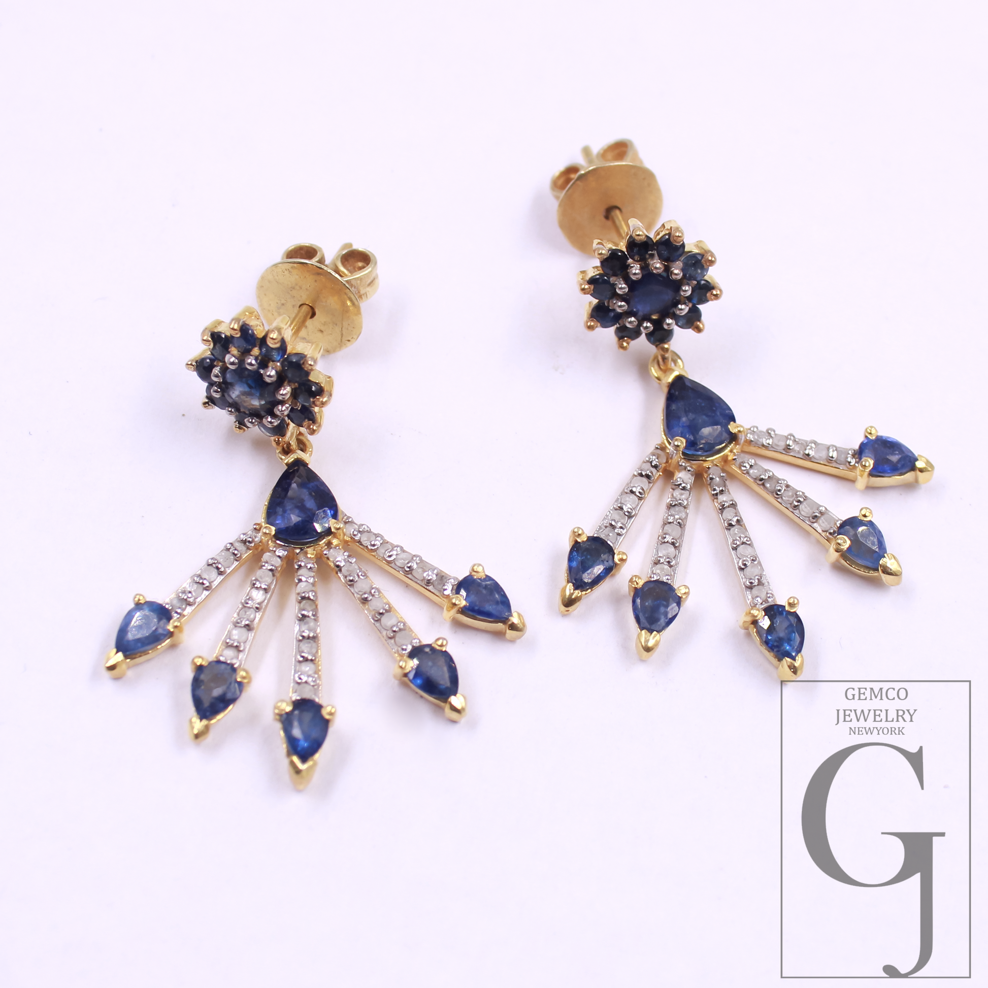 Gold earrings with blue gemstones on a white background, featuring Gemco Jewelry branding.