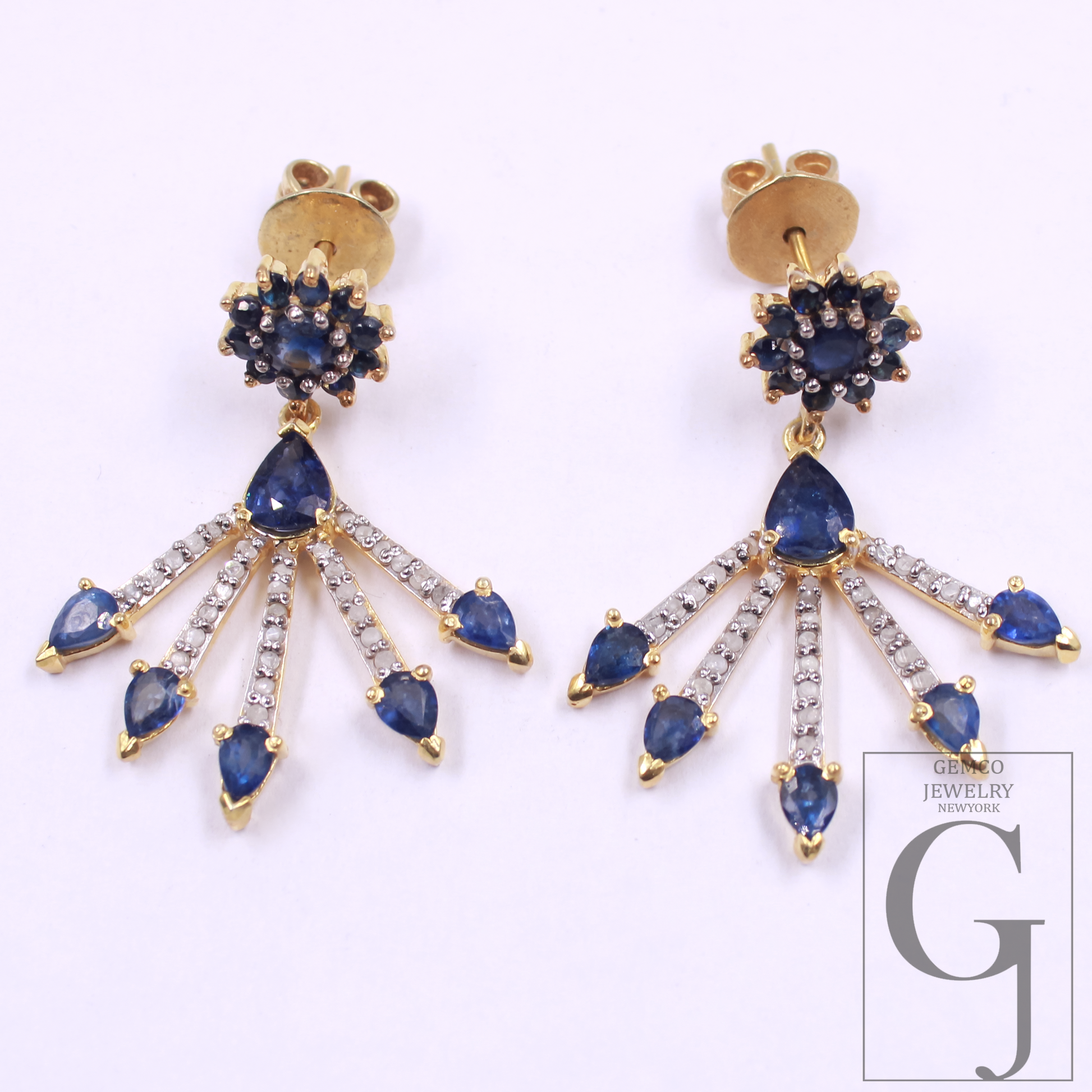 Pair of gold earrings with blue gemstones and clear stones on a white background