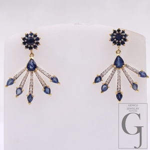 Pair of blue gemstone earrings on a white stand with Gemco Jewelry branding.