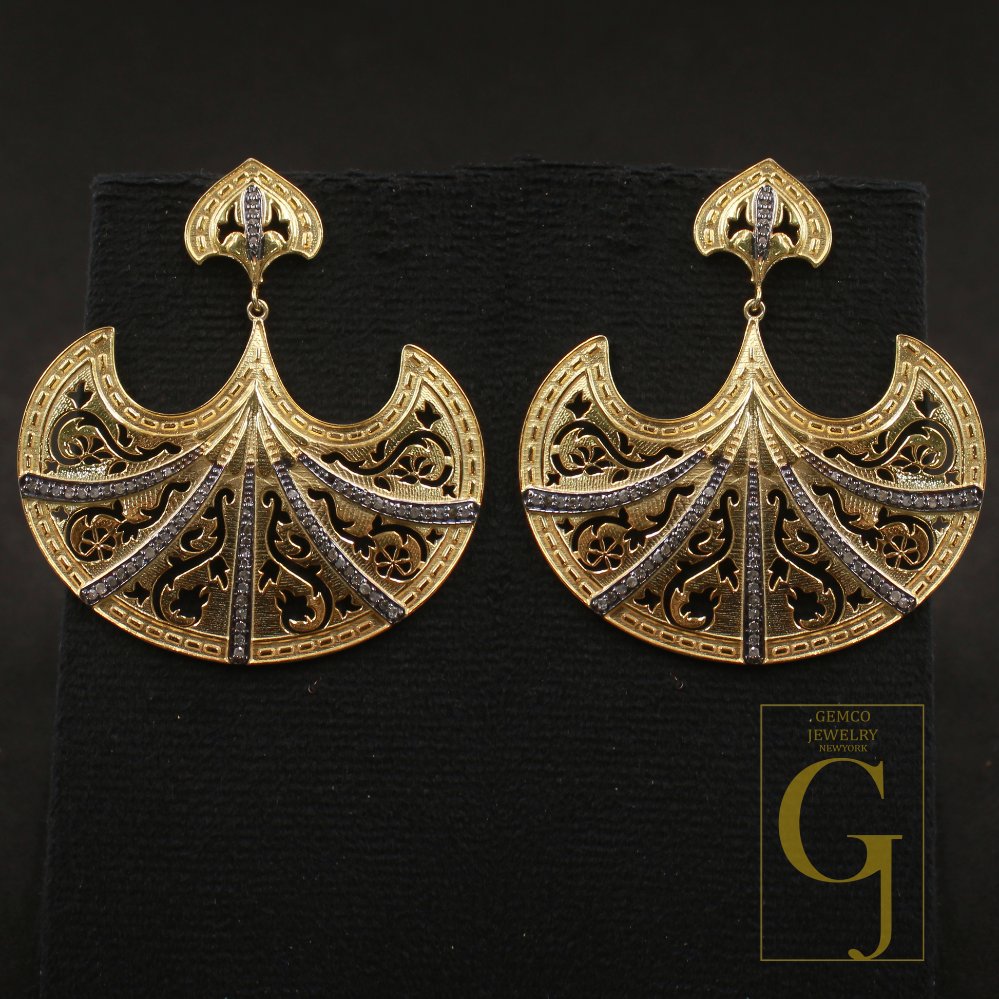 Gold earrings with intricate designs on a black background