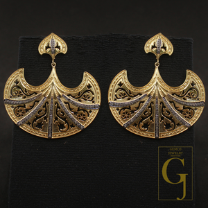 Gold earrings with intricate designs on a black background