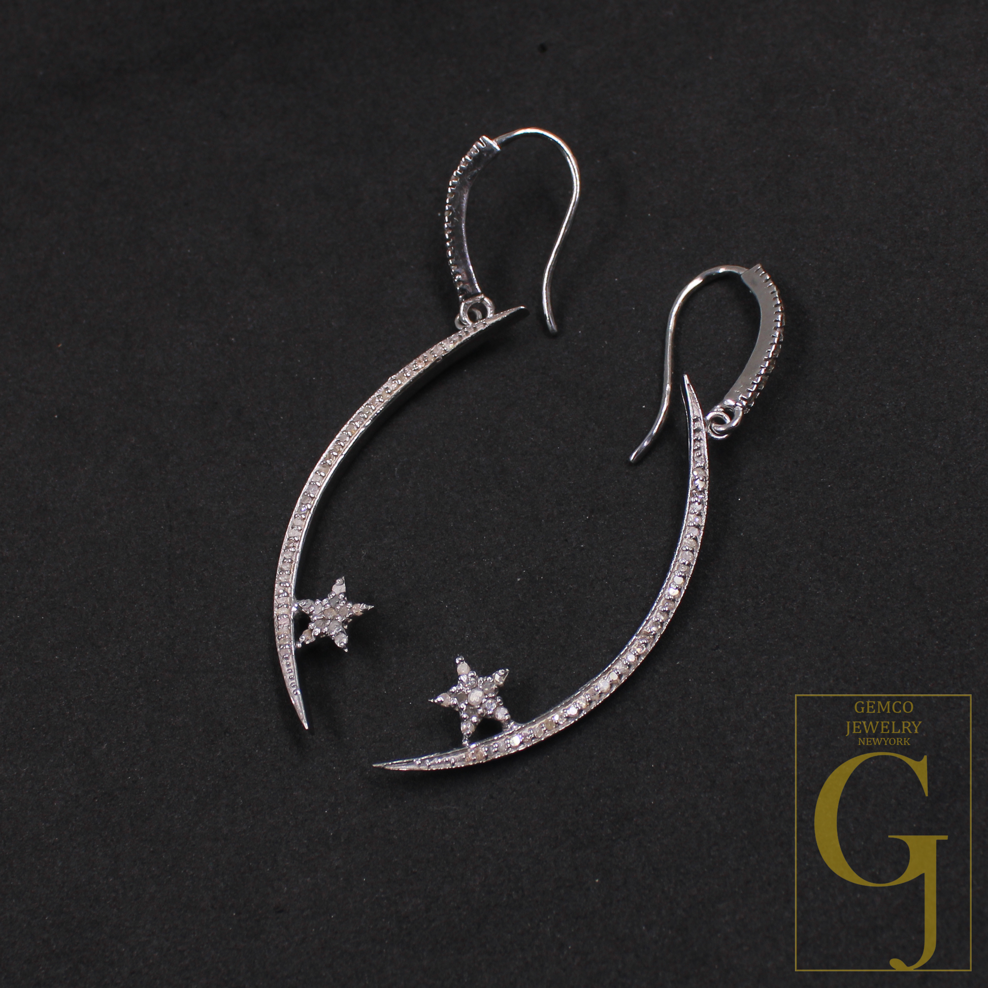 Silver earrings with star designs on a dark background, featuring Gemco Jewelry logo.