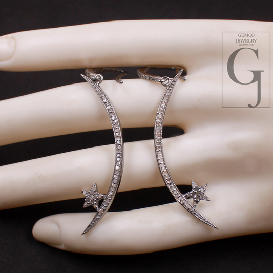 Silver earrings with star details on a hand, brand 'GEMCO JEWELRY' visible