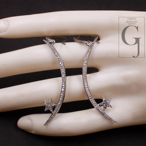 Silver earrings with star details on a hand, brand 'GEMCO JEWELRY' visible