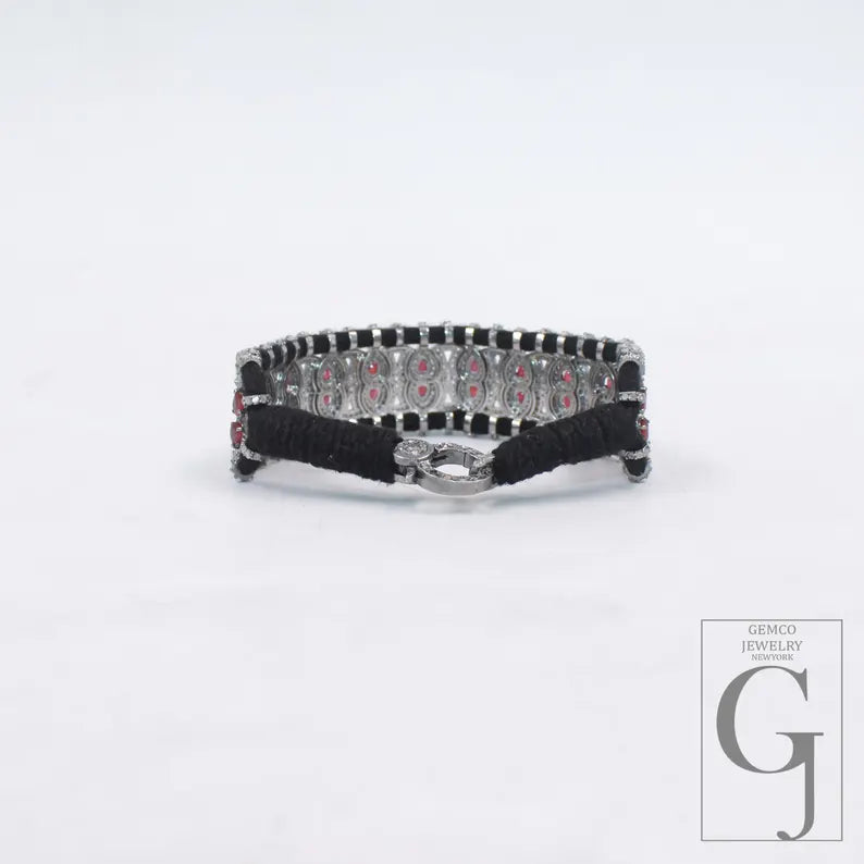 Black bracelet with red stones on a white background, featuring Gemco Jewelry logo.