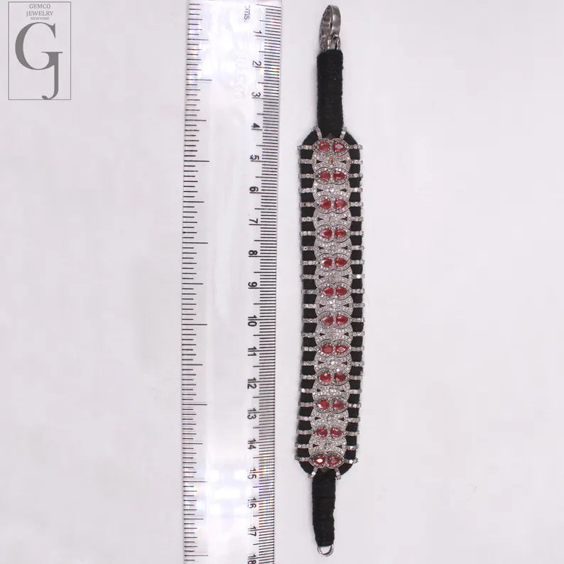 Decorative belt with red gemstones next to a ruler on a white background