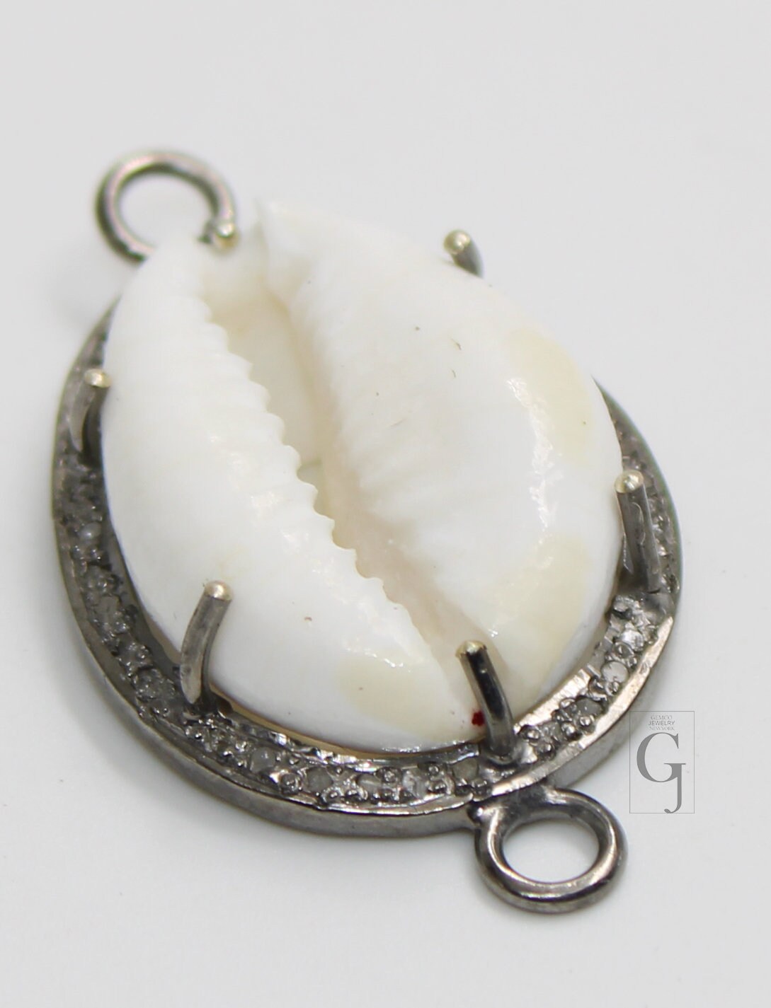 A sterling silver oxidised handmade diamond charm pendant featuring a cowrie design with pave diamonds around the edge.