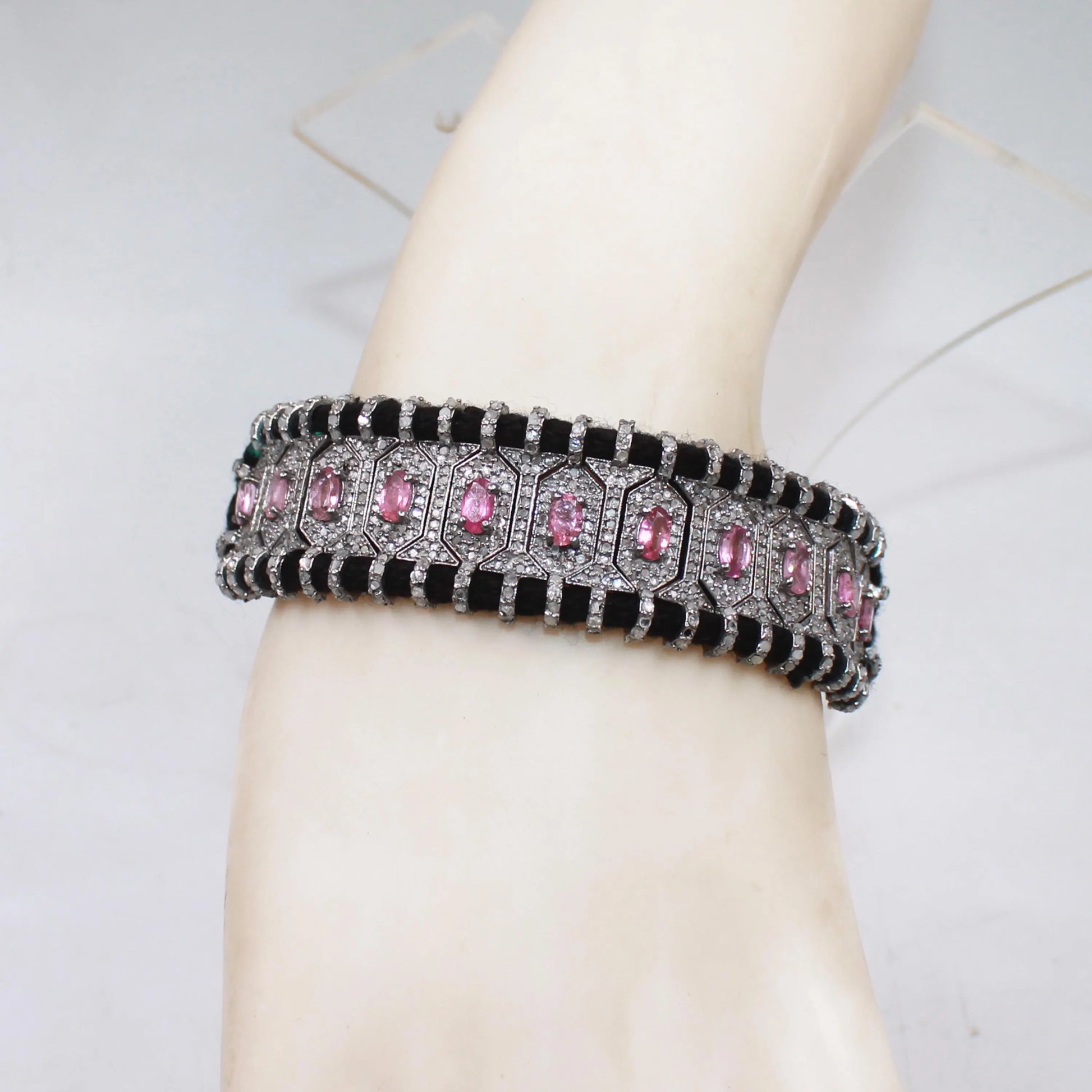 Bracelet with pink stones on a mannequin arm against a tiled wall background