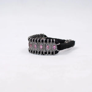 Black hair tie with pink and clear gemstones on a white background