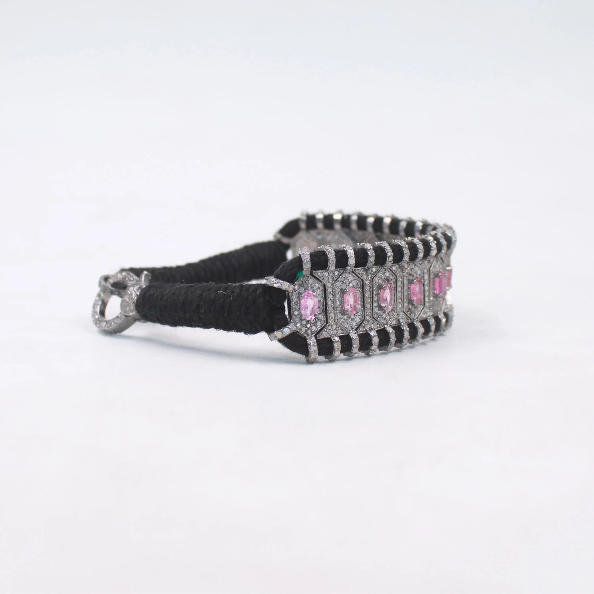 Bracelet with black strap and pink gemstones on a white background