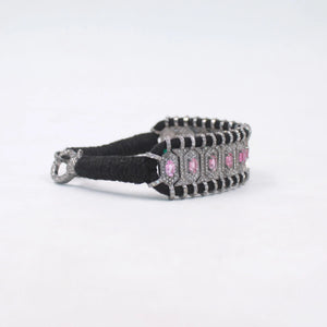 Bracelet with black strap and pink gemstones on a white background